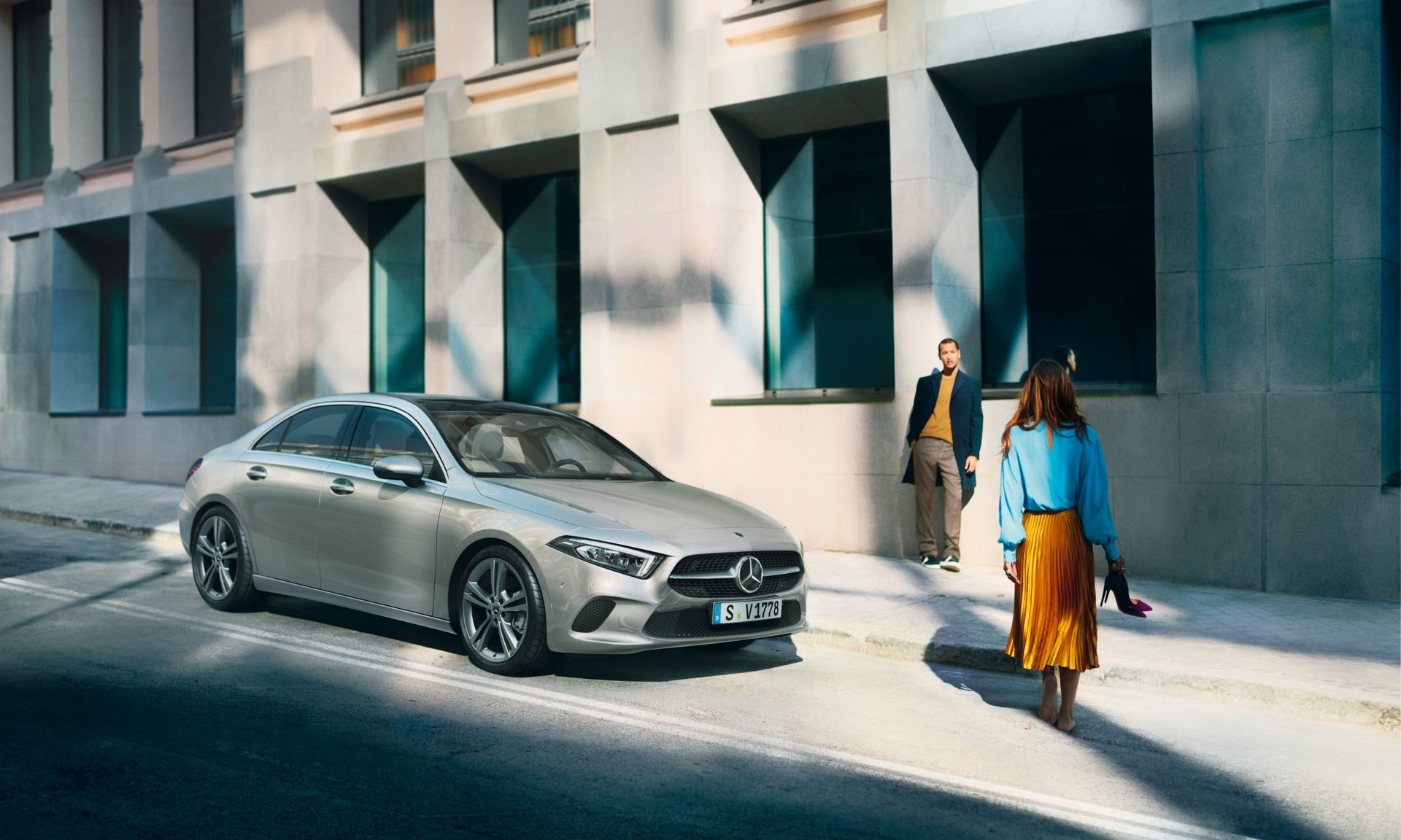 Grauer Mercedes steht vor einem Gebäude.